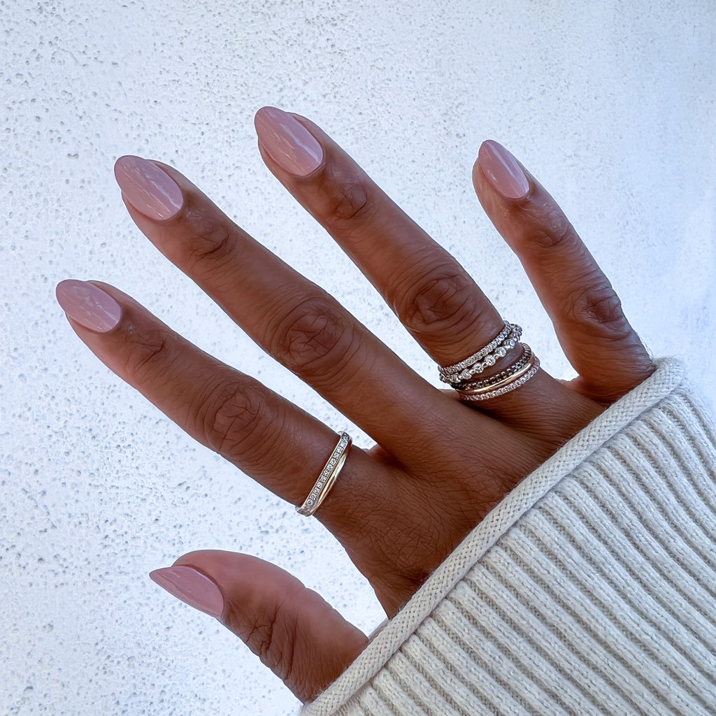 Hand with almond-shaped nails painted in Poodle neutral beigey pink showing a sleek at-home manicure look