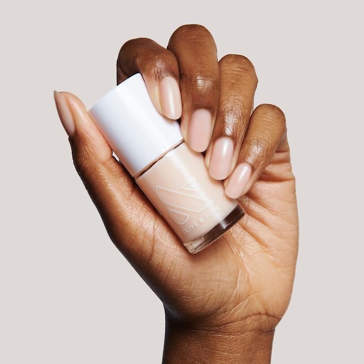Hand holding a neutral polish bottle from THE STARTER SET with smooth nails for a simple at-home manicure