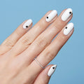 Hand with white polish and single black star nail stickers on each nail for Stars manicure against blue background thumbnail