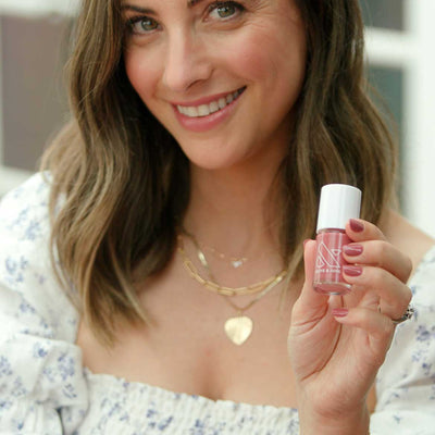 Hand with nails painted in Fig Ranch gel polish by Olive and June holding a matching bottle for a smooth mani Fig Ranch figgy pink Nail Polish