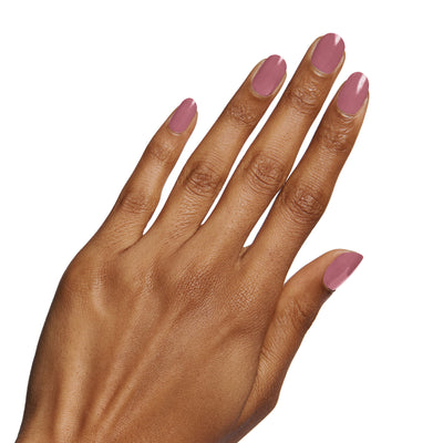 Hand with nails painted in Fig Ranch gel polish by Olive and June holding a matching bottle for a smooth mani Fig Ranch figgy pink Nail Polish