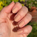 Hand showing nails polished in Howdy neutral beige with terracotta undertones in natural sunlight outdoors