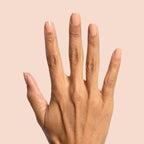 Hand displaying smooth neutral beige nails painted with Howdy polish against a soft peach background