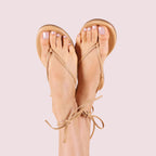 Feet with toes painted in Potpourri sheer mauve quick dry gel polish wearing beige strappy sandals on pale pink background