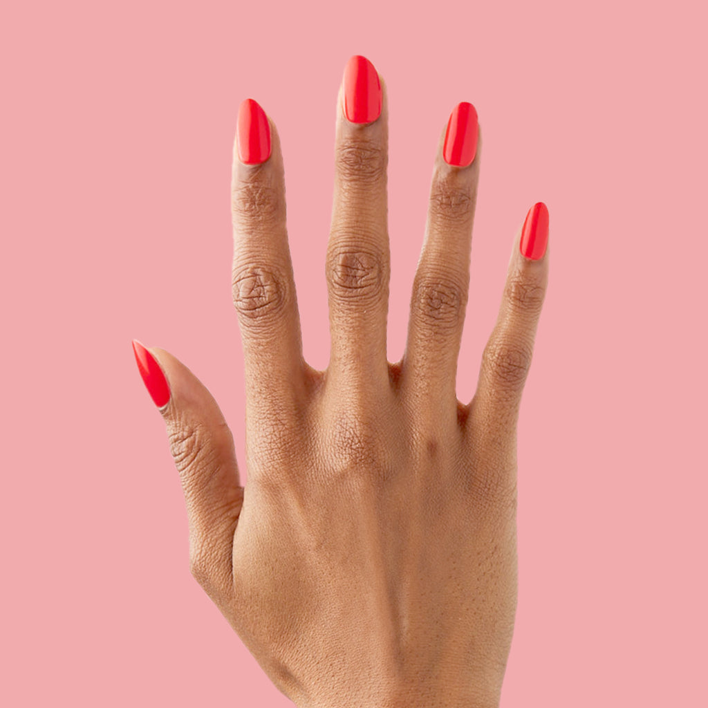 Lava - Press-On | Medium | Almond showing hand with medium almond false nails in vibrant spicy orange red polish on pink background