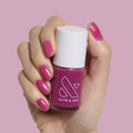 Hand with nails painted in magenta purple polish holding Olive and June This Lettuce is Radicchio nail polish bottle