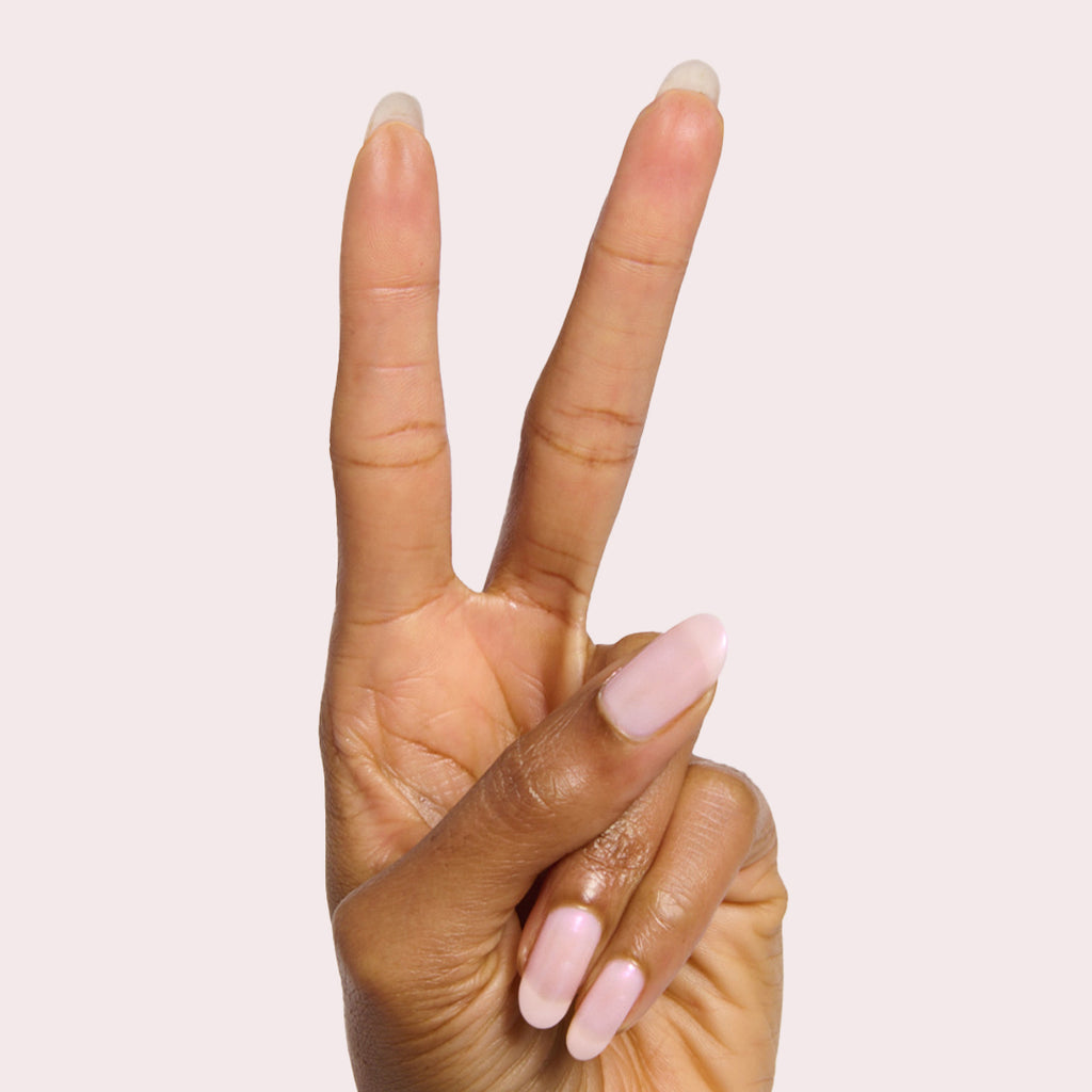 Hand showing two fingers with milky pink iridescent Pink Capiz nail polish for a delicate manicure look