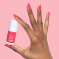Hand with Pomodoro quick dry nail polish bottle and matching vibrant pinky-tomato red manicure on nails