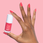 Hand with Pomodoro quick dry nail polish bottle and matching vibrant pinky-tomato red manicure on nails