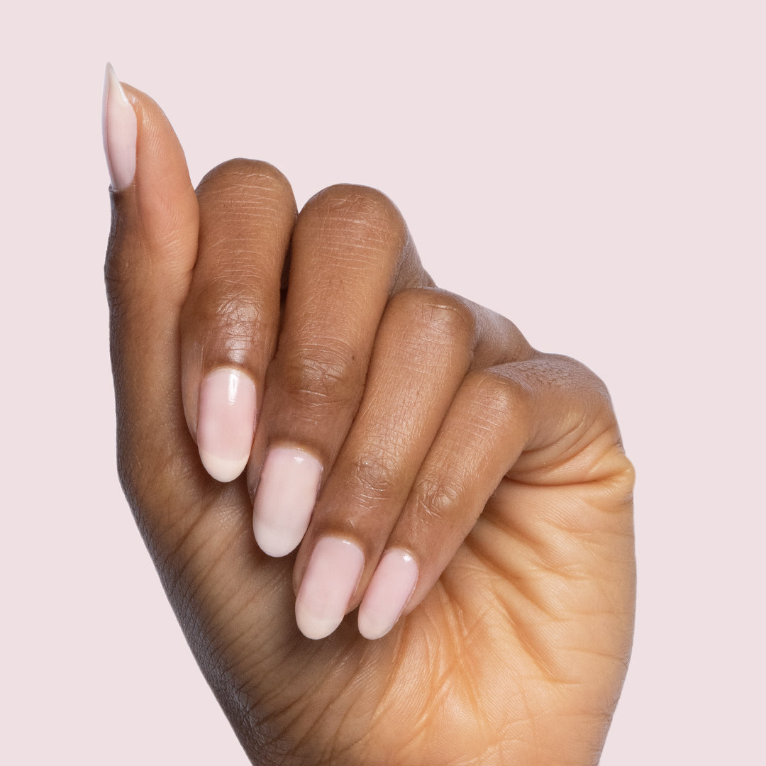 Hand with almond-shaped nails painted in sheer mauve Potpourri quick dry gel polish on pale pink background