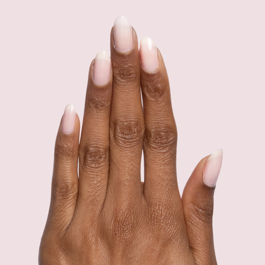 Hand with neutral-shaped nails painted in sheer mauve Potpourri quick dry gel polish on light pink background