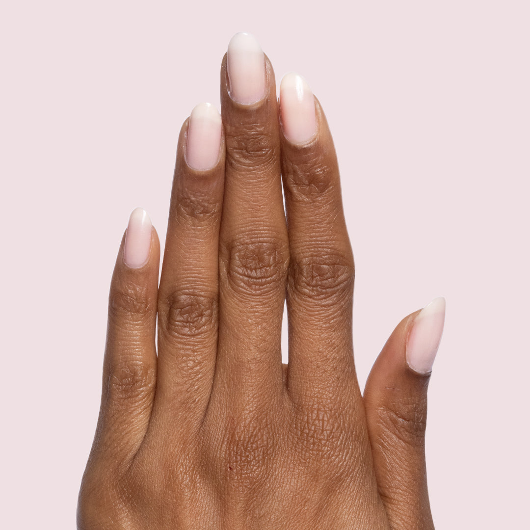 Hand with neutral-shaped nails painted in sheer mauve Potpourri quick dry gel polish on light pink background