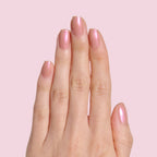Hand with natural nails painted in glossy Sandy Scallop gel polish showing a soft milky golden iridescent manicure