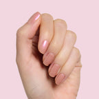Hand with natural nails coated in Sandy Scallop showing a creamy golden iridescent long-lasting gel polish manicure