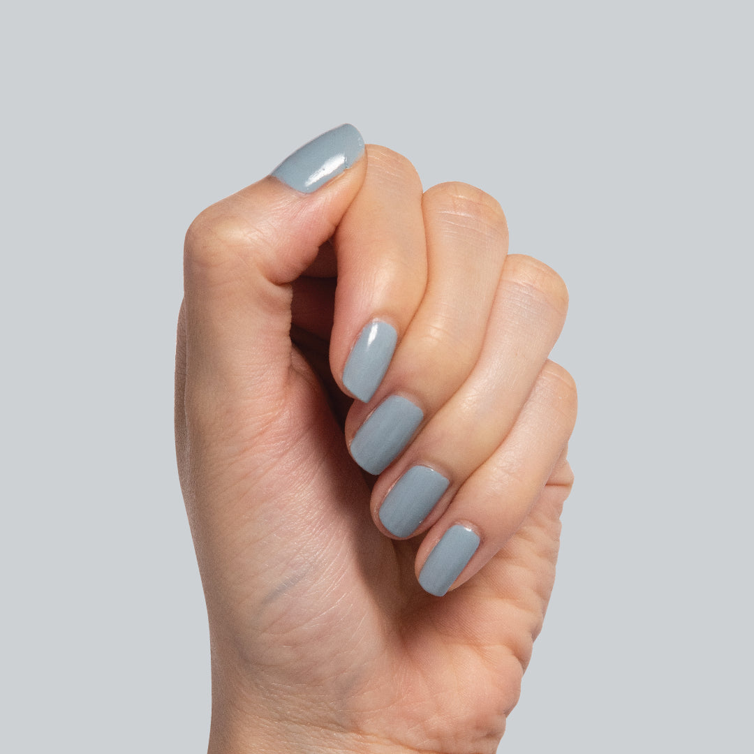 Hand with nails painted in Vintage denim blue polish showcasing a smooth at-home manicure by Olive and June