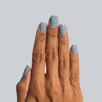 Hand with nails painted in Vintage blue polish for a classic denim-inspired at-home manicure by Olive and June